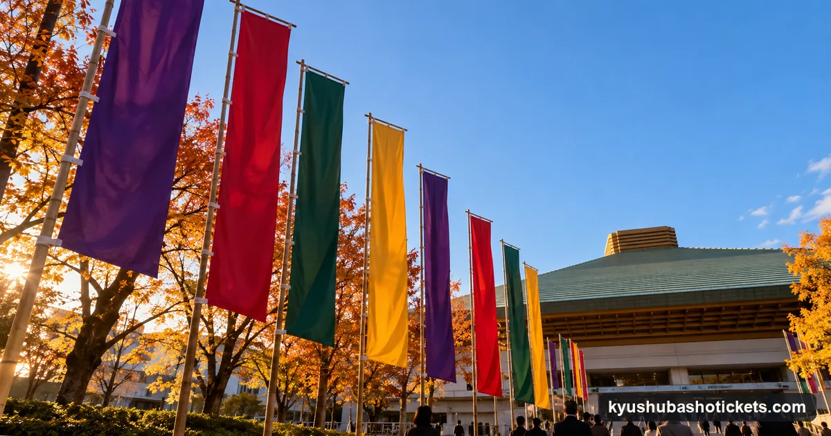 Tall coloured cloth banners on poles outside an arena under a clear autumn sky